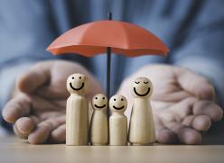 Picture of a wooden toy family under a red umbrella