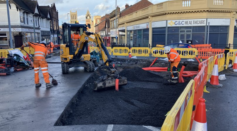 Highways crews in orange high vis uniform working on a road.