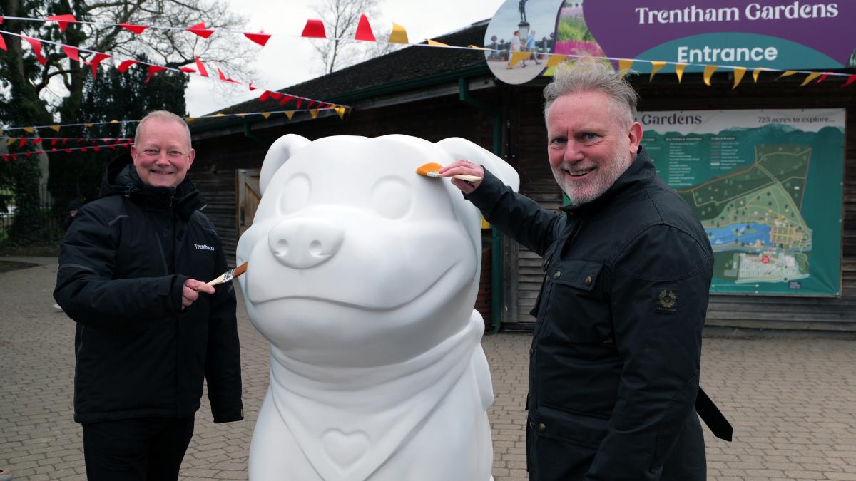 Two men stood either side of a giant white sculpture of a Staffordshire Bull Terrier called Staffy, which is the county's new visitor mascot.