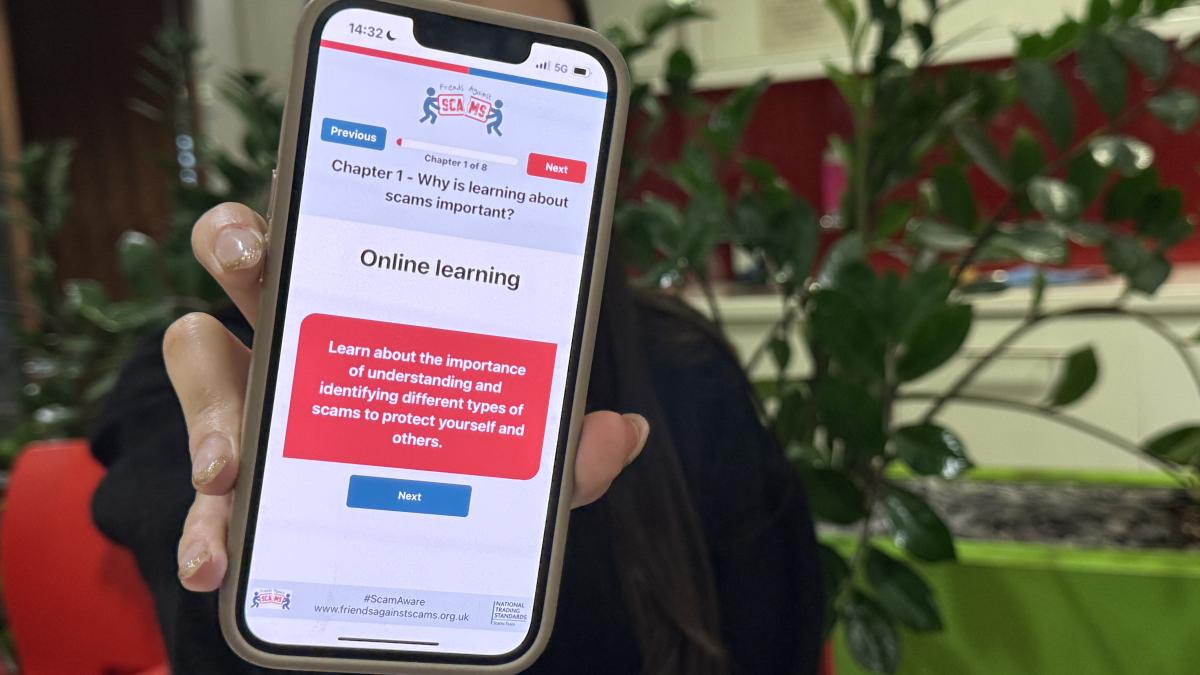 Talia holding up phone with Friends Against Scams website